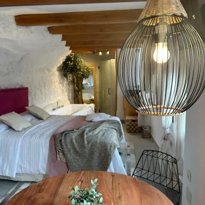 Imagen de la habitación de Mon Amour en la que se puede apreciar la cama, la mesa y la lampara de primer plano.