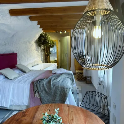 Imagen de la habitación de Mon Amour en la que se puede apreciar la cama, la mesa y la lampara de primer plano.