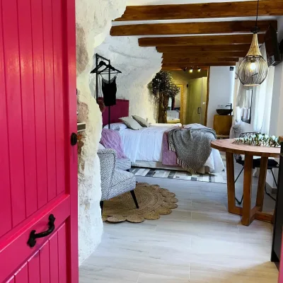 Imagen de la habitación de Mon Amour con detalles en rosa, la puerta es rosa y las paredes son de roca blanca ya que esta dentro de la montaña.