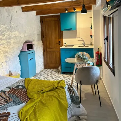 Imagen en la que se puede observar la cocina de Frida, la mesa con dos sillas, especial para parejas y la cama.